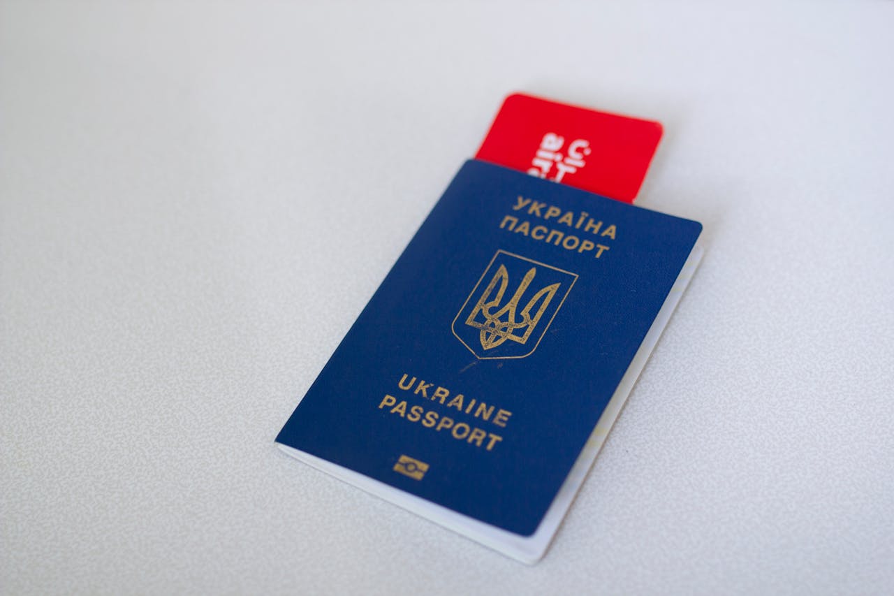 Blue Ukraine passport with airplane ticket on white surface. Travel concept.